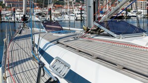 A sailboat docked at a marina with a wooden deck and multiple masts.