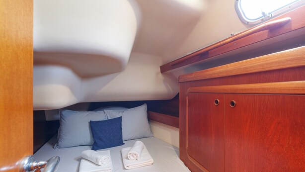 A compact cabin with a bed, pillows, and neatly folded towels.