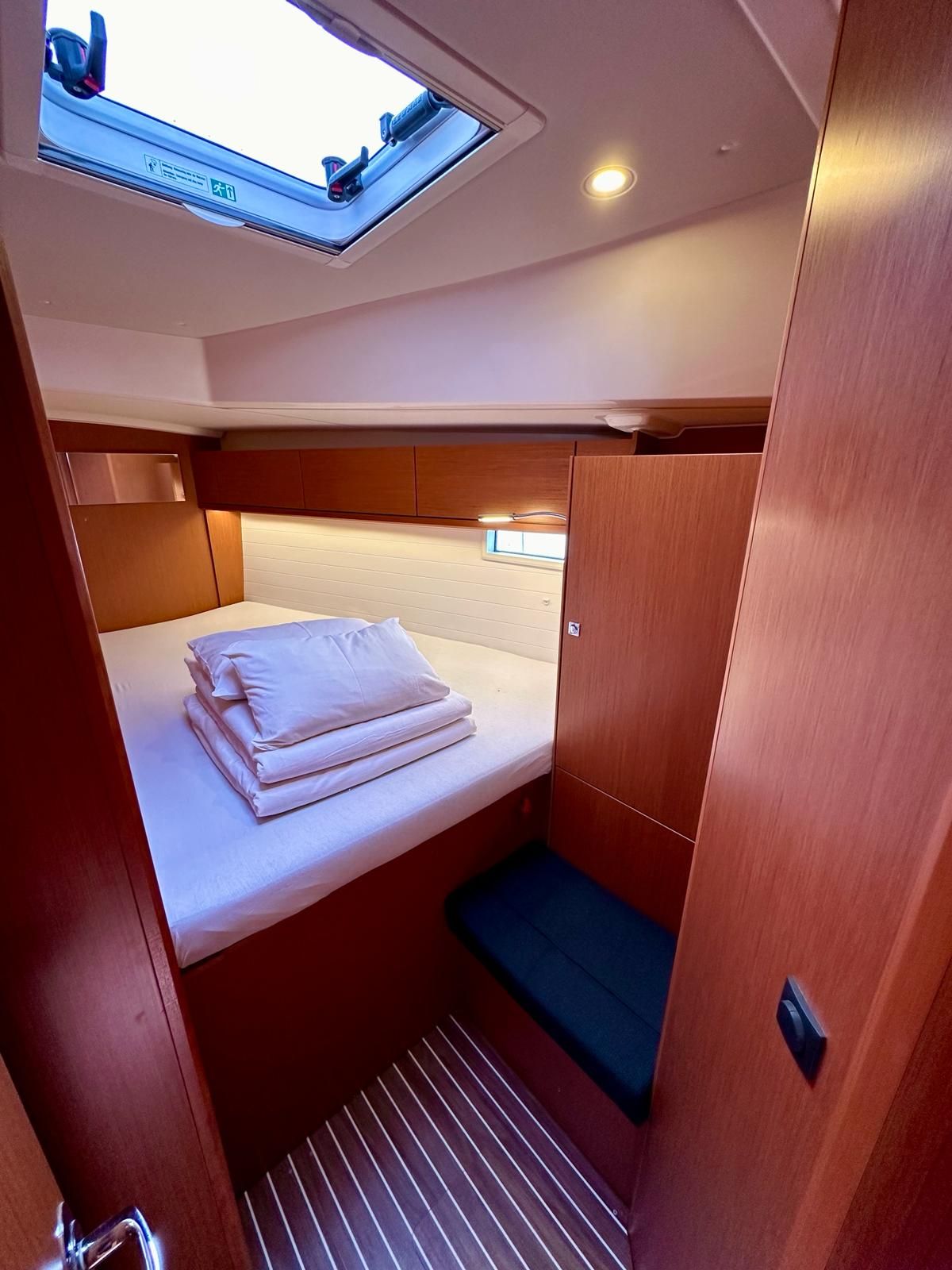 A compact cabin with a bed, a skylight, and a small seating area.