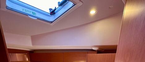 A compact cabin with a bed, a skylight, and a small seating area.