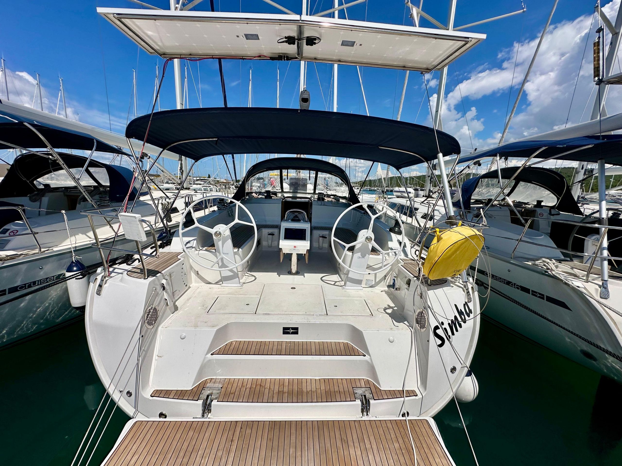 A sailboat docked at a marina with a steering wheel, a small control panel, and a yellow life buoy.