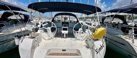 A sailboat docked at a marina with a steering wheel, a small control panel, and a yellow life buoy.