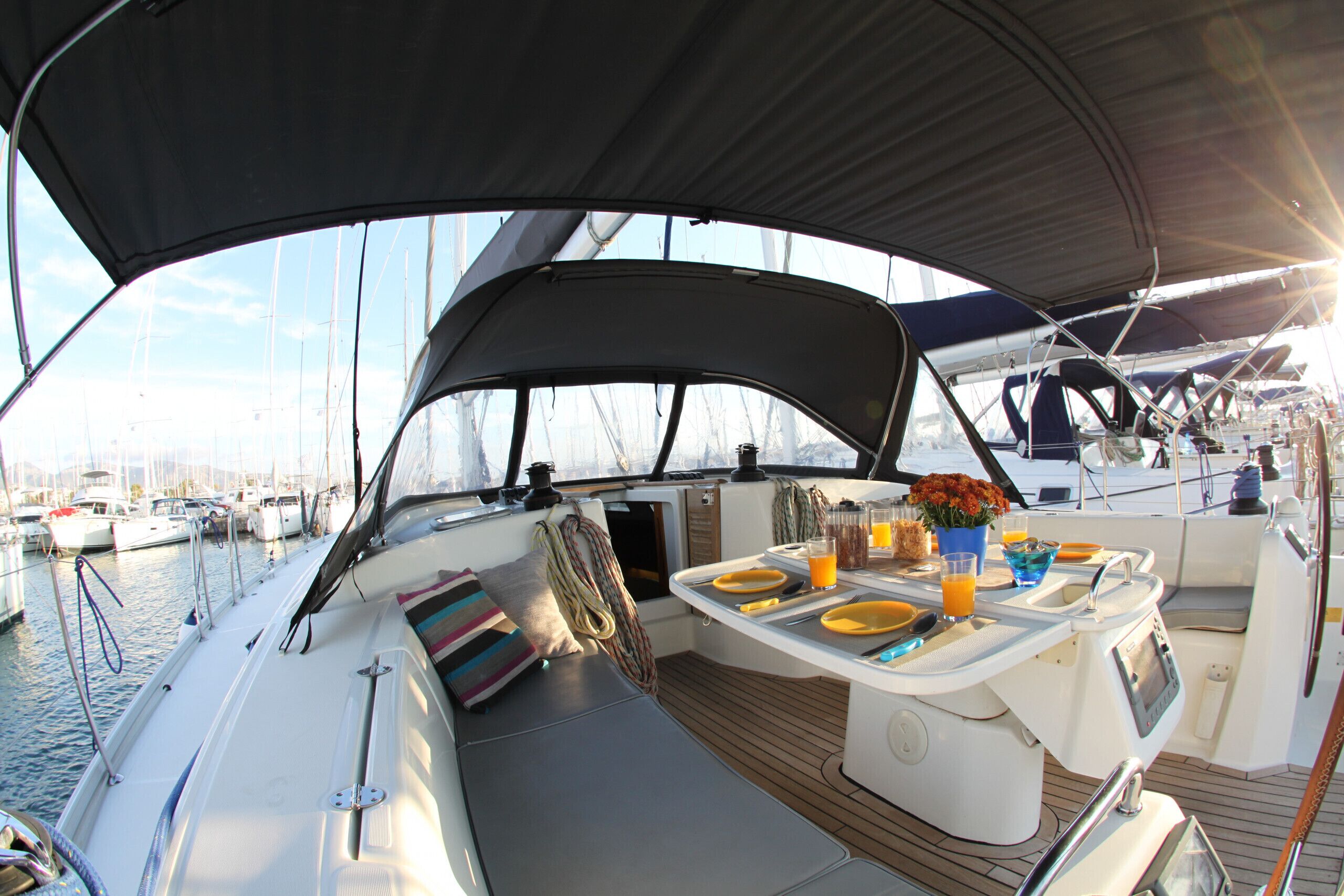 A boat deck with a dining table, seating, and a view of the marina.