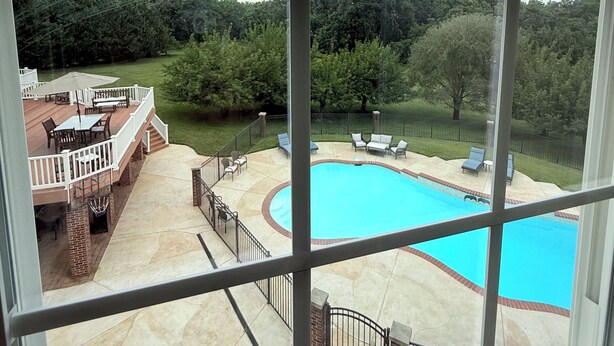 Vista de un patio trasero con piscina, muebles de terraza y área cercada.