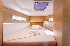 A compact bedroom with a skylight, wooden walls, and a bed with neatly folded white towels. - Sun-Kissed Sailing Adventure in Zadar, Croatia (Zadar)