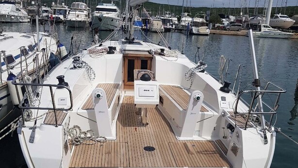 A boat docked at a marina with a wooden deck, multiple masts, and a clear sky. - Sun-Kissed Sailing Adventure in Northern Croatia (Punat)