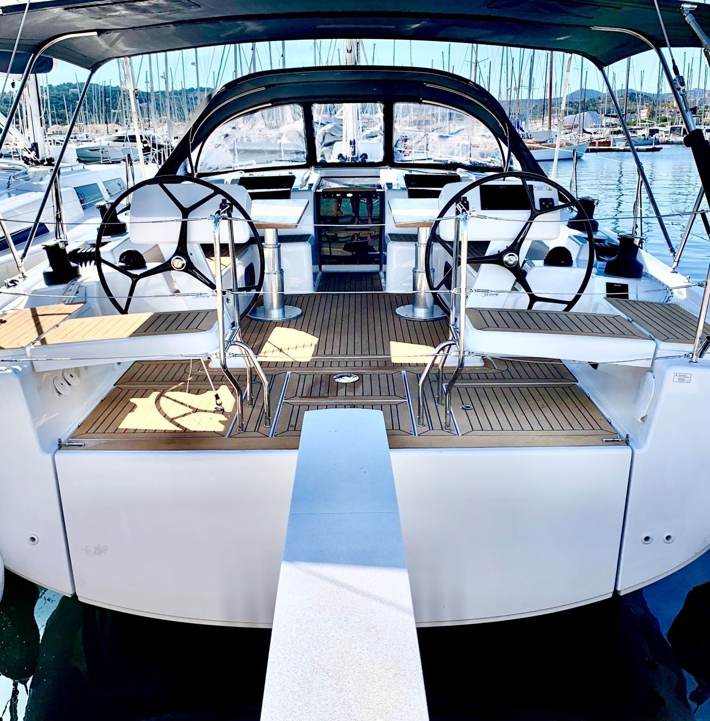 A boat's deck with a steering wheel, control panel, and seating area.