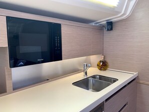 A modern kitchen with a built-in microwave, a stainless steel sink, and a decorative bottle.