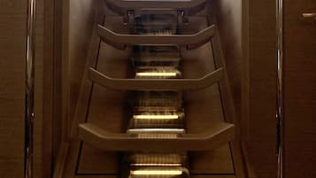 Ein modernes Interieur mit einer zentralen Treppe, einem Fenster oben und einer Tür rechts.