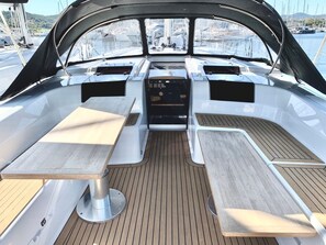 A boat's interior with a central table, two side tables, and a control panel.