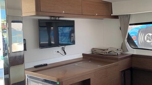 Eine kleine Küchenzeile mit Flachbildfernseher, Fernbedienung und einem kleinen Tisch.