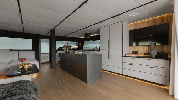 Una cucina moderna con isola centrale, mobili integrati e una TV a schermo piatto.