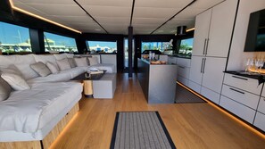 Un intérieur moderne comprenant un canapé, une table basse, un coin cuisine et une vue dégagée grâce à de grandes fenêtres.