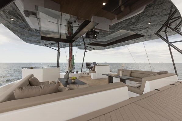 A spacious deck with a modern design, featuring a seating area with sofas and a table, and a view of the sea.
