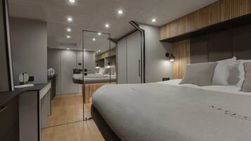 A modern bedroom with a large bed, a wooden headboard, a mirror, and a bedside table.