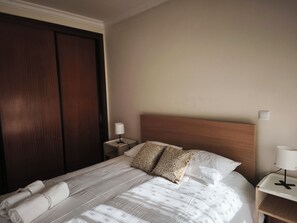 A hotel room with a bed, a nightstand, a lamp, and a wardrobe. - Excellent apartment in Matosinhos Sul. Very close to the beach and the subway. (Matosinhos)