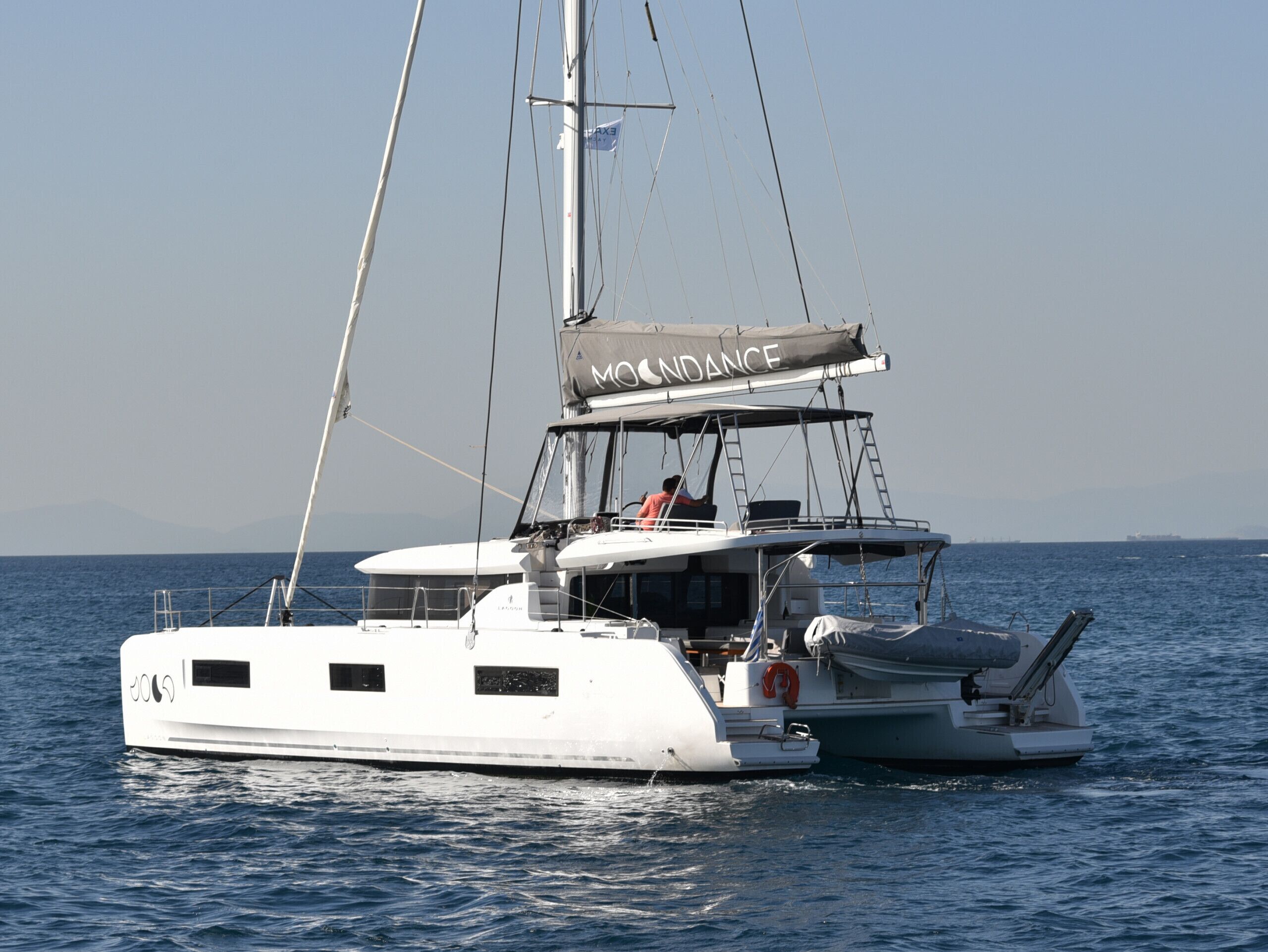 Eine weiße Yacht mit Kabine, Mast und Rettungsboje.