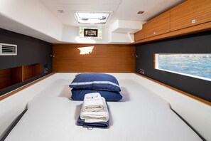 Una habitación compacta con cama, ventana con vistas, tragaluz y paneles de madera.