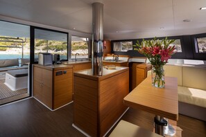 Eine moderne Küche mit Holzschränken, einer zentralen Kochinsel und Blick auf das Meer.