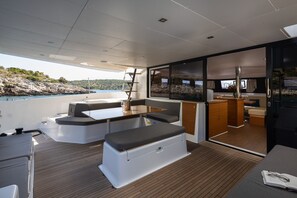 Un interior de barco moderno con comedor, asientos y cocina.