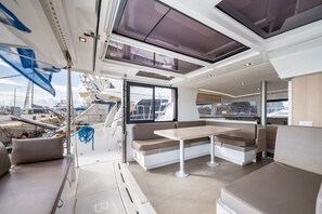 Ein modernes Yacht-Interieur mit Essbereich, Sitzgelegenheiten und Blick auf den Yachthafen.