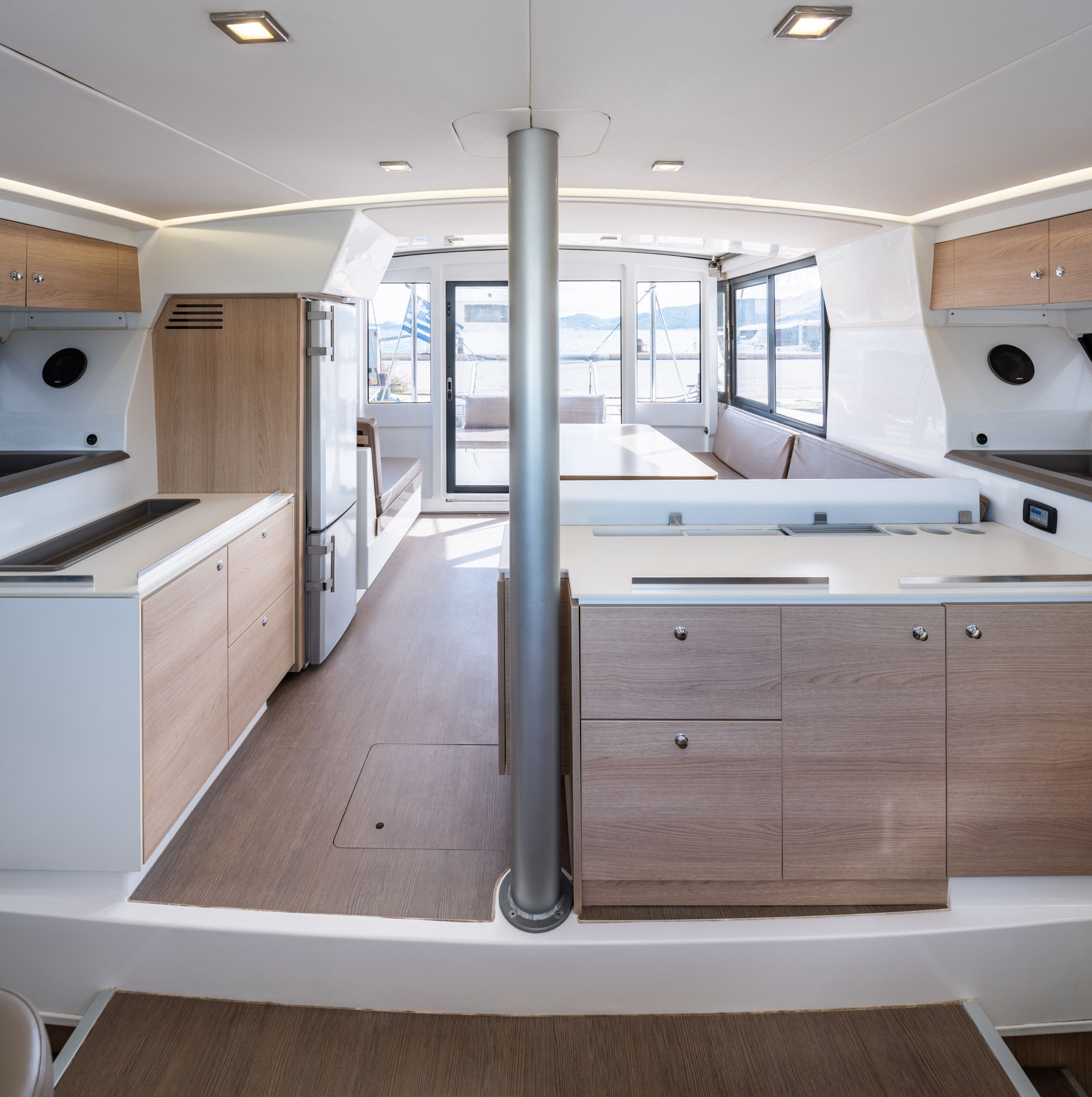A modern kitchen with a central island, wooden cabinets, and a view through the windows.