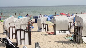 Beach huts with numbers, a sandy beach, and the sea in the background. - Apartment mit Strandkorb in Uckeritz (Ueckeritz)