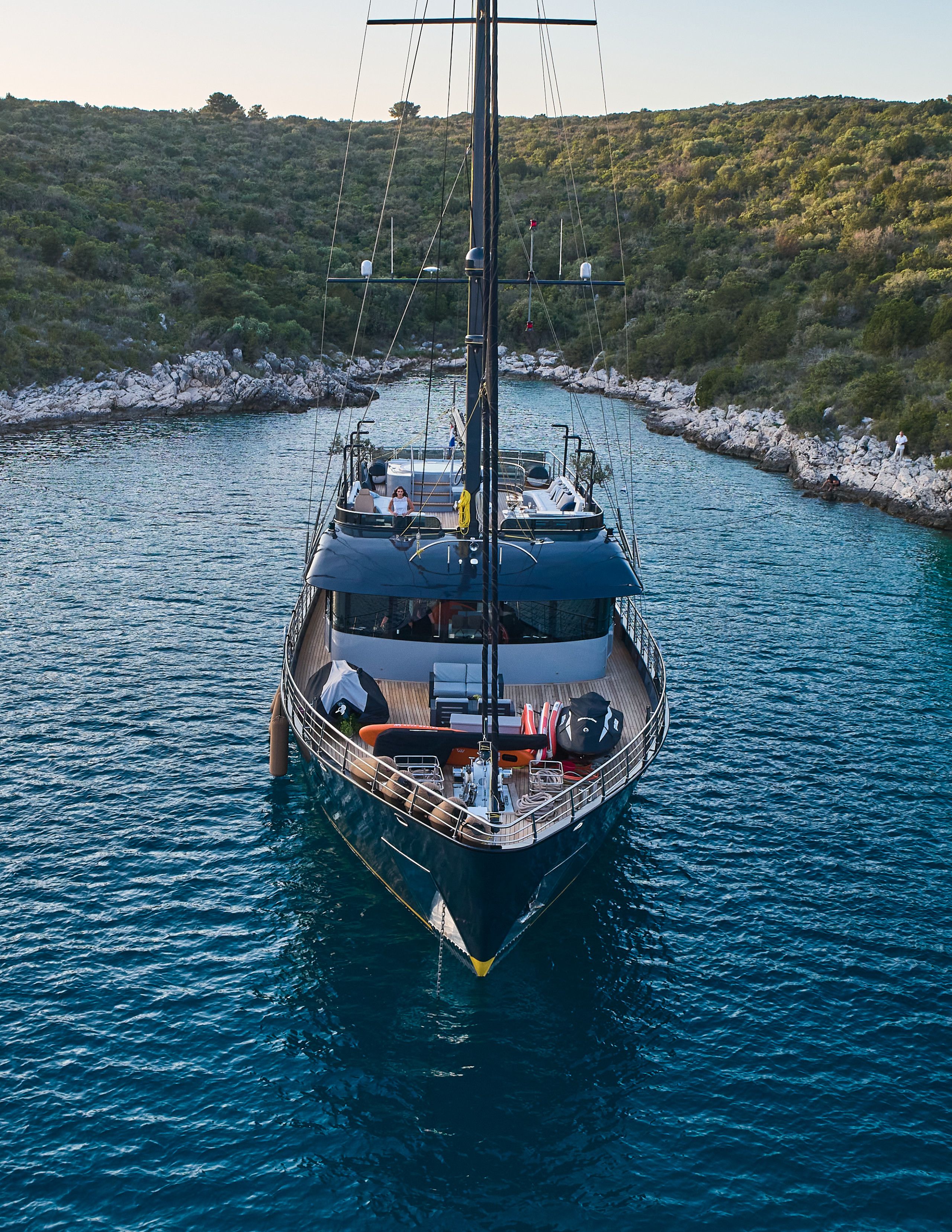 A large yacht docked at a marina with a deck area featuring seating and a small table.