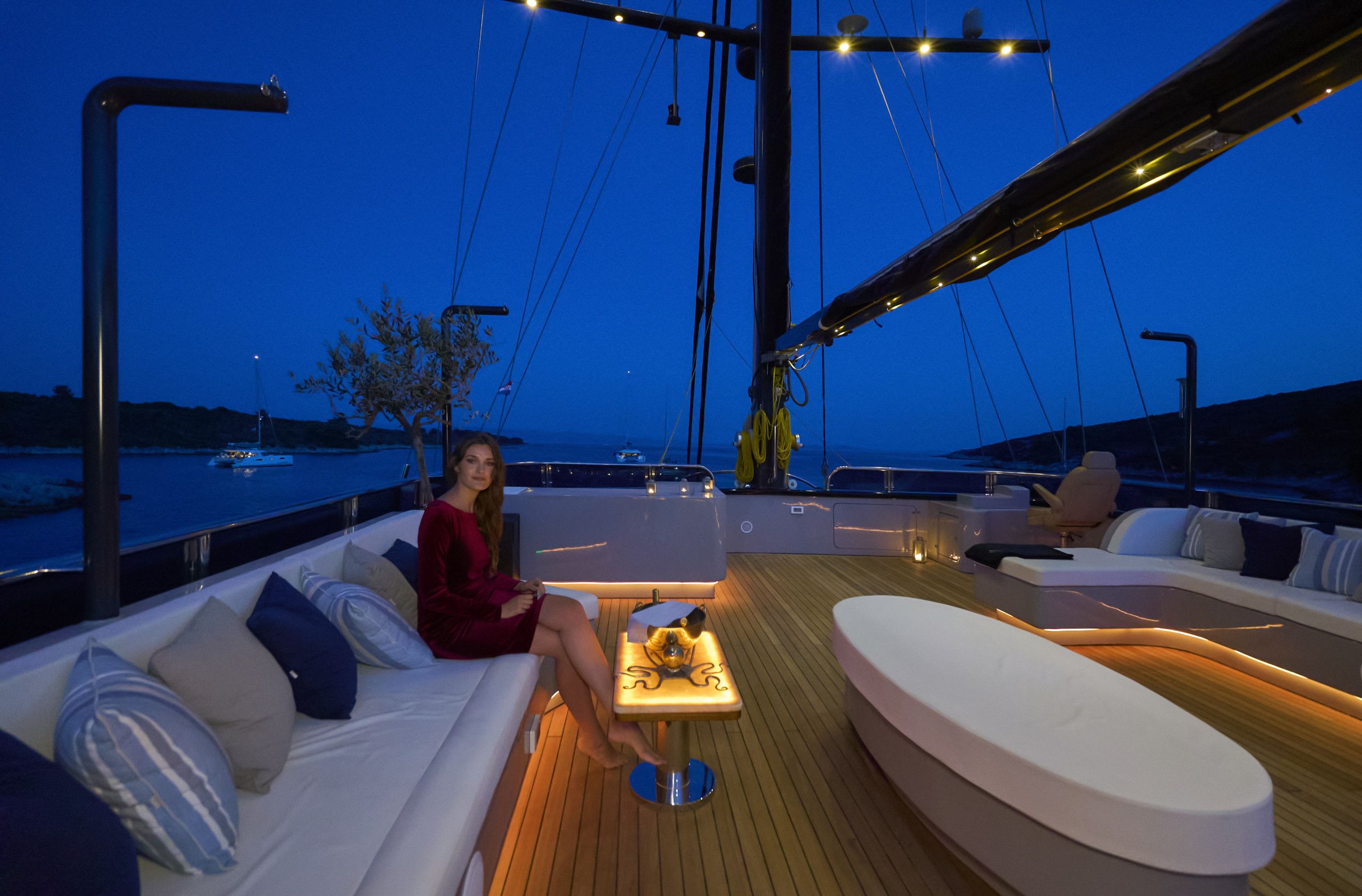 A yacht deck with a sofa, a small table, and a hanging light fixture.