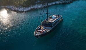 A large yacht with a spacious deck, a helipad, and a swimming area.
