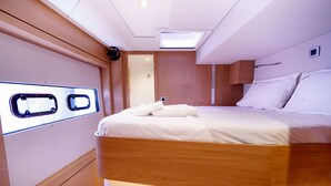 Habitación pequeña y luminosa con una cama individual, un tragaluz y un ventanal.