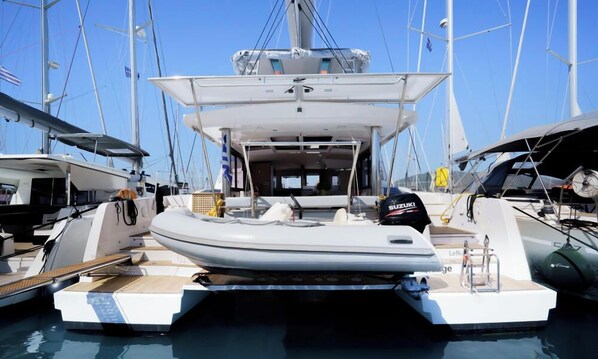 A yacht docked at a marina with a covered deck area, a visible cabin, and a motor.