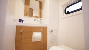 Un baño con tocador de madera, espejo, dispensador de toallas y ventana.