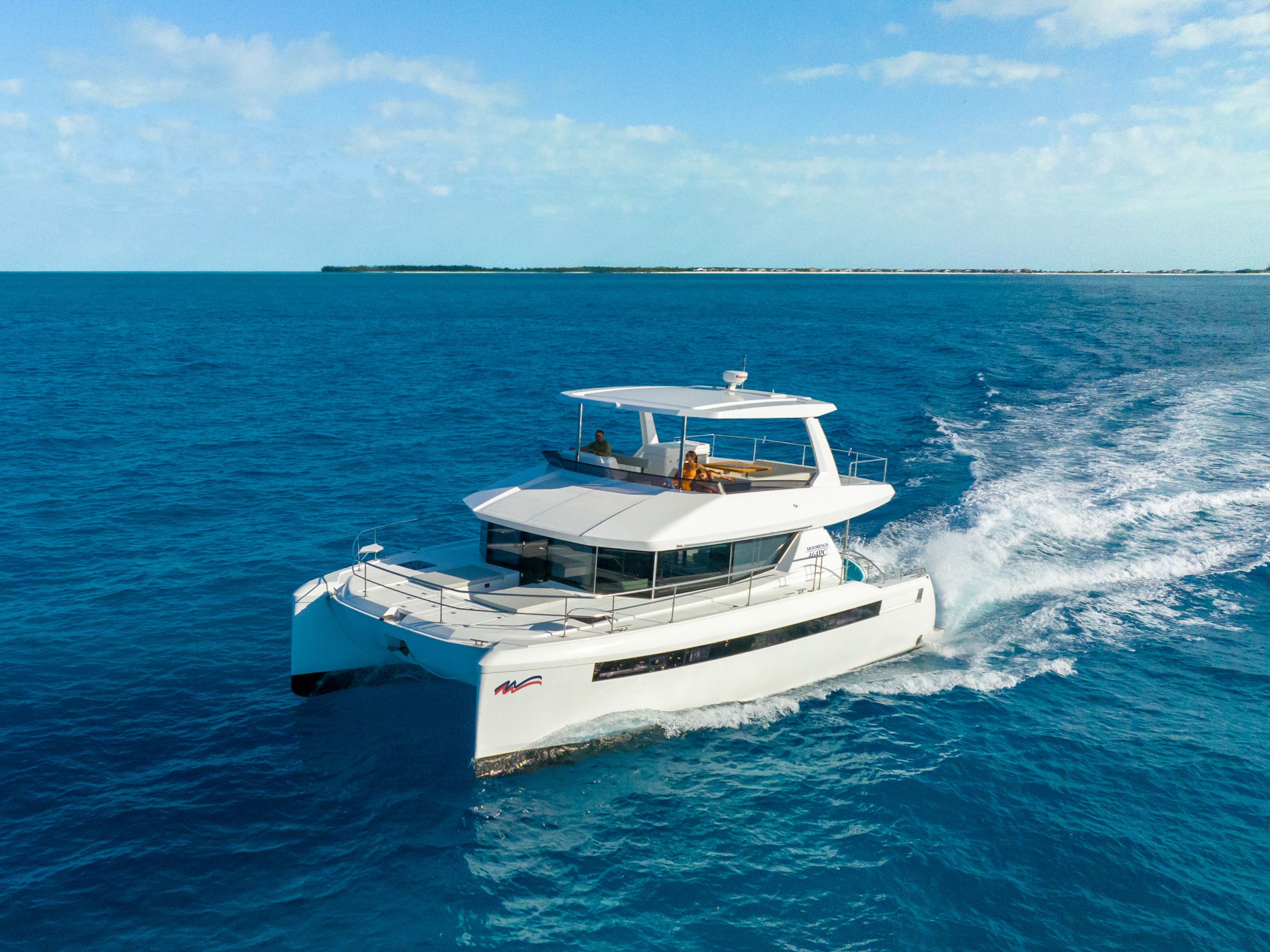 Un yacht blanc doté d’une cabine et d’un pont couvert, naviguant sur une mer calme.