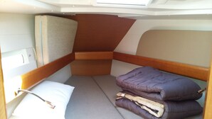 A compact, well-organized sleeping area with a bed, pillows, and a storage compartment.
