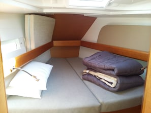 A compact, well-organized sleeping area with a bed, pillows, and a storage compartment.