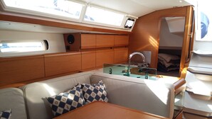 A compact galley with a sink, stove, and seating area with cushions.