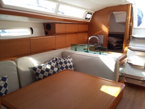 A compact galley with a sink, stove, and seating area with cushions.