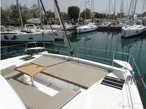 Ein Yachthafen mit vertäuten Booten, ein Holztisch auf dem Deck und eine ruhige Wasseroberfläche.