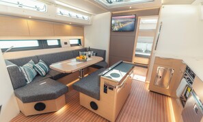 A compact interior with a sofa, a small table with fruits, a TV, and a compact kitchenette.