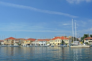 Un port de plaisance où sont amarrés de nombreux bateaux, dont un grand voilier, et des bâtiments aux toits rouges.