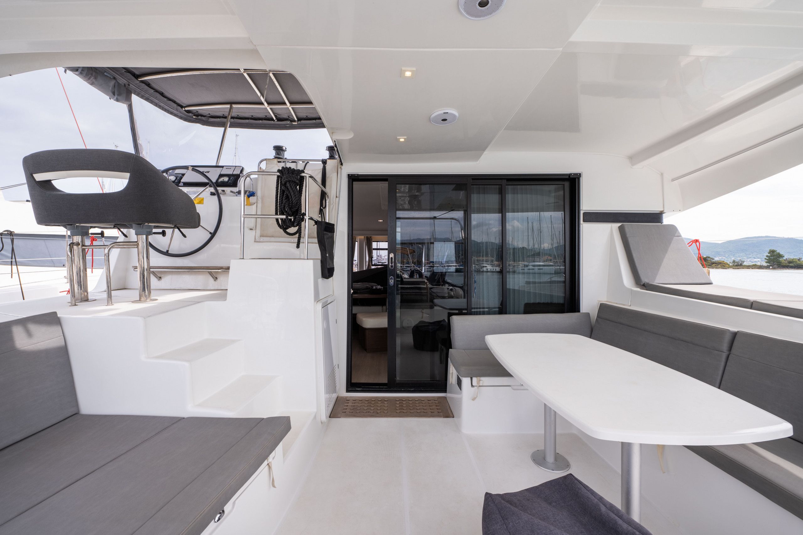 A modern boat interior with a dining area, seating, and a control station.