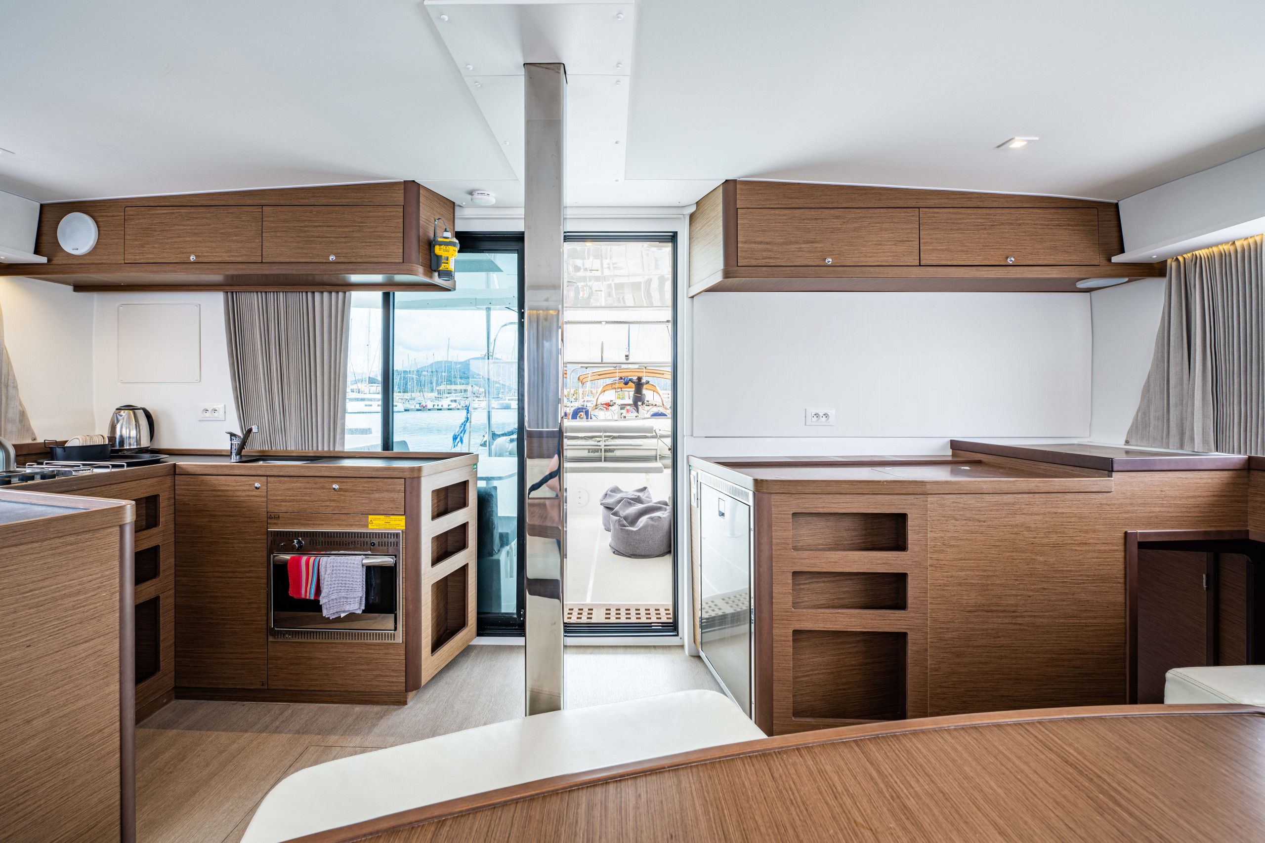 A modern kitchen with wooden cabinets, a built-in oven, and a view of the marina.