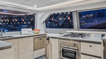 A modern kitchen with a built-in oven, a gas stove, and a large window overlooking a cityscape.