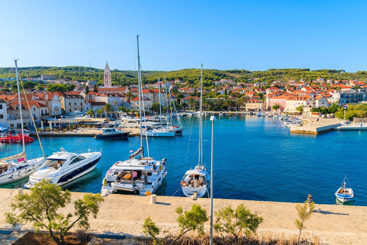 A marina with boats docked, a town in the background, and a prominent church tower.