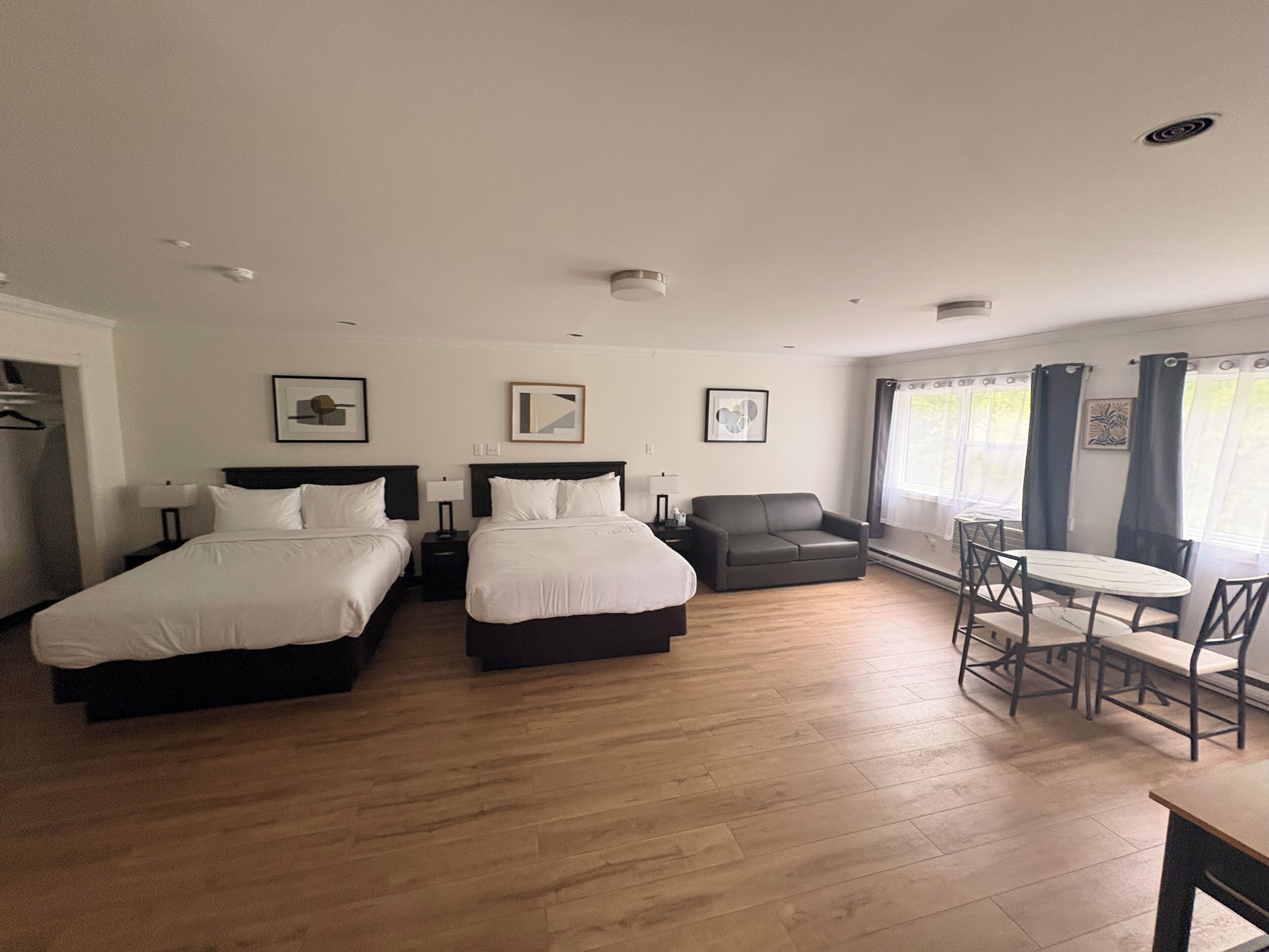 Une chambre d’hôtel avec deux lits, un canapé, une table à manger et une fenêtre avec des rideaux.