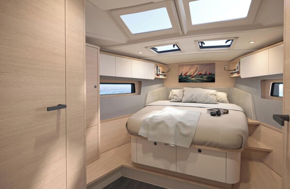 Une chambre à coucher compacte et bien éclairée, avec un lit, des fenêtres de toit et un tableau.