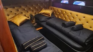 A room with two reclining chairs, a tufted headboard, and a television screen.