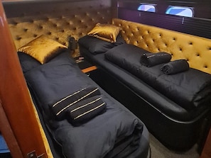 A room with two reclining chairs, a tufted headboard, and a television screen.