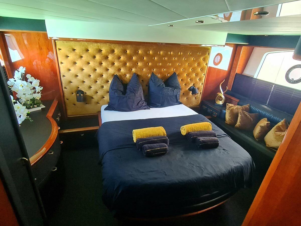 Ein Schlafzimmer mit einer gepolsterten Kopfteile, einem Bett mit blauer Bettwäsche, zwei Kissen und einem Nachttisch mit Lampe.